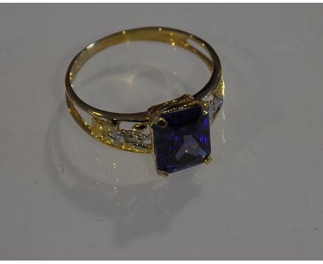 A blue topaz and diamond dress ring, claw set in a 9ct yellow gold band with open shoulder
