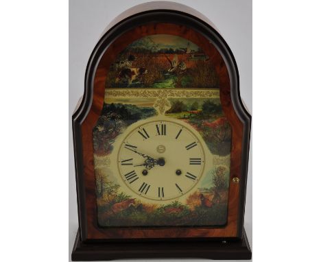 A modern cherrywood veneer cased mantel clock with German movement, the face with Roman numerals and decorated with scenes on