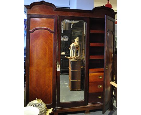 A mahogany wardrobe, the central door with full length beval mirror flanked by two moulded doors beneath two arches pedements