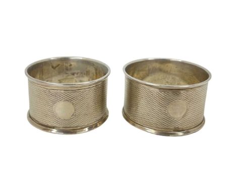 Pair of Silver Napkin Rings. 27 g. Birmingham 1943, 'EJE'. Engine turned finish, vacant cartouche on each,Diameter 4.3 cmsCon