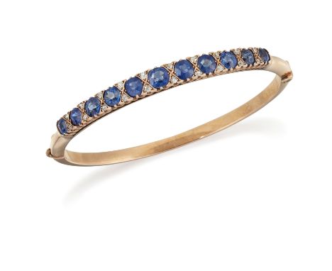 A SAPPHIRE AND DIAMOND BANGLE, the eleven graduated oval cushion cut sapphires, total estimated approx. 4.81cts, interspaced 