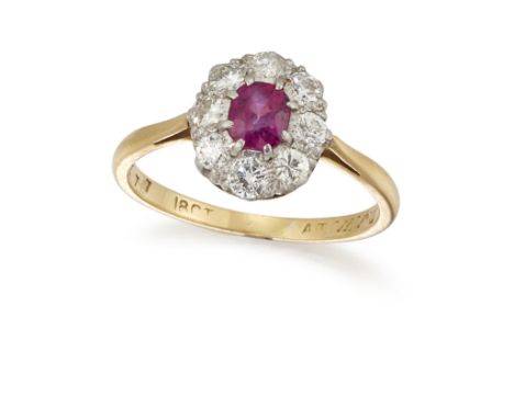 A RUBY AND DIAMOND CLUSTER RING, the oval cut ruby set within a surround of eight brilliant cut diamonds, between open taperi