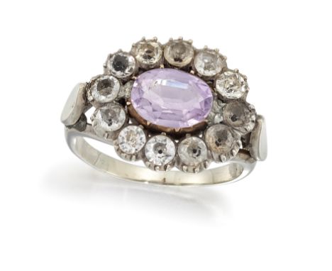 AN AMETHYST AND PASTE RING, the oval amethyst in rubover mount, surrounded by white paste stones with closed backs, with trif