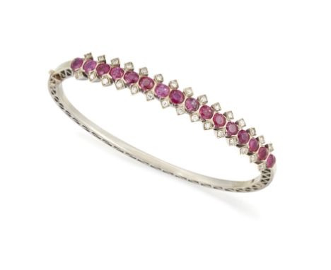 A RUBY AND DIAMOND HINGED BANGLE, the sixteen oval rubies, total estimated approx. 3.70ct set with a single cut diamond above