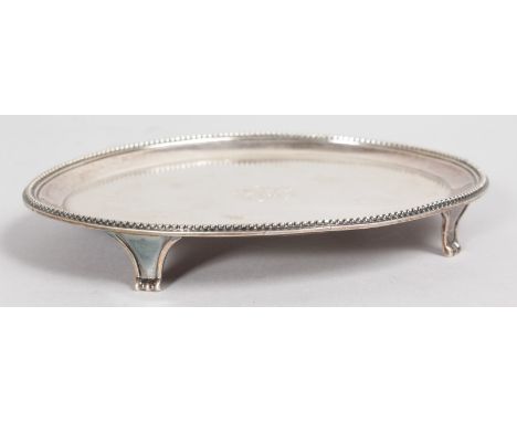 A GEORGE III OVAL TEAPOT STAND with beaded edge on four curving legs. 6ins long.  London 1784.  Maker: EI.