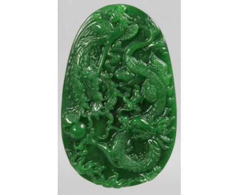 A LARGE CHINESE CARVED GREEN JADE OVAL PENDANT carved with dragons.