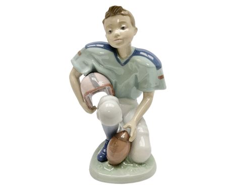 Lladro figure, Football Player, modelled as a young boy playing American football in kneeling position, sculpted by Joan Code