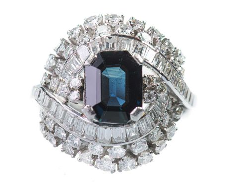 A SAPPHIRE AND DIAMOND CLUSTER RING an octagonal-cut blue-green sapphire within a fancy scroll border of round and baguette-c