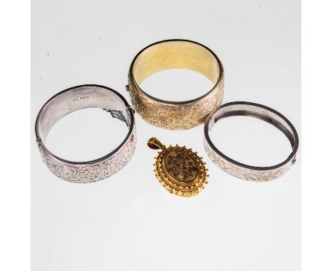A LATE 19TH CENTURY GILT METAL LOCKET PENDANT AND THREE BANGLES the locket with foliate engraved decoration and a beaded bord