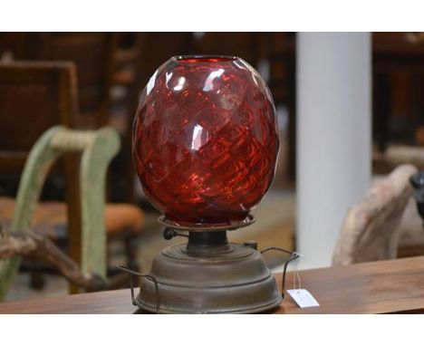 A 1ate 19th century brass oil lamp with a large dimpled ruby glass shade. Shade height 26cm