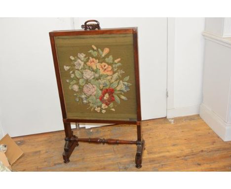 A William IV mahogany fire screen, the sliding panel with scroll carved panel over a silk upholstered screen, raised on trest