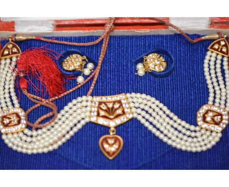 An Indian cultured pearl, paste, enamel and silk cord necklet, mounted in yellow metal, the central plaque  with a stylised f