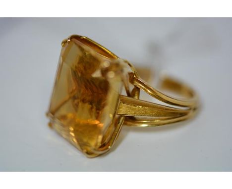 A striking large citrine dress ring, the emerald-cut stone claw-set on split shoulders, the yellow gold band unmarked. Gross 