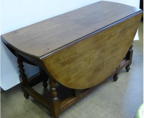 A George III Mahogany Oval Gate Leg Dining Table, the dining table having turned supports with straight stretchers and ball f