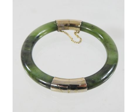 A jade and yellow metal mounted bangle, of hinged design