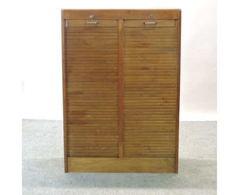 A 1920's light oak double tambour front office cabinet, fitted with adjustable shelves, 83cm