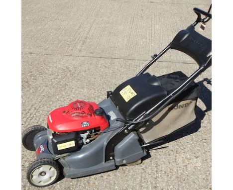 A red Honda HRX 426 petrol driven lawnmower, with manual