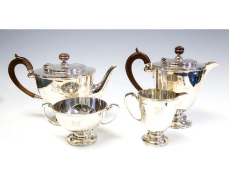 A George V silver four piece tea service comprising teapot, hot water jug, milk jug and sugar bowl, plain bodies with chased 