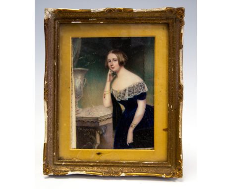 A mid 19th Century portrait miniature, circa 1830's, a young lady, half length standing next to a console table wearing a blu