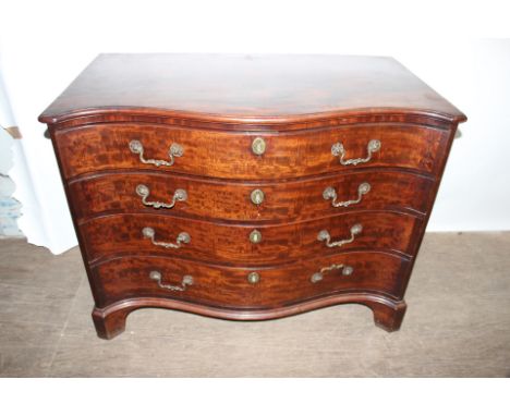 A George III and later mahogany chest of drawers, of serpentine form, fitted with four long graduated drawers, raised on brac