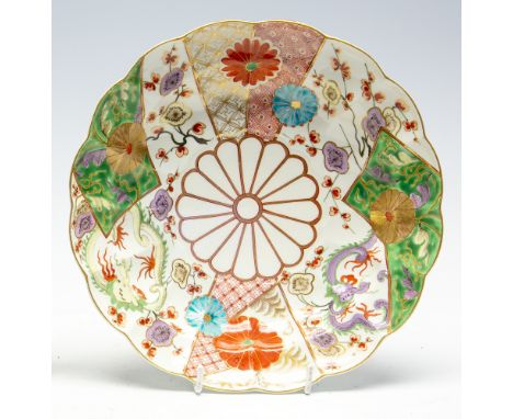 A Worcester deep plate, brocade pattern with a lobed rim, painted in the Japanese taste with panels of dragons, prunus flower