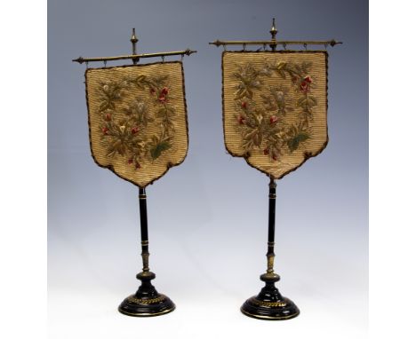 A pair of Victorian table top pole screens, silk backed woolwork panels, black glazed ceramic stands, height 52cm (2)