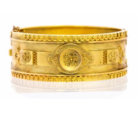 A Victorian Etruscan style yellow metal bangle, the Etruscan style applied decoration to the front section, with applied scro