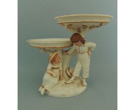 A Royal Worcester Kate Greenaway double comport, ivory and gilt, each dish supported with a tree stump and branches, with a b