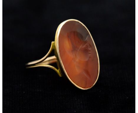 A orange agate oval intaglio ring, the intaglio possibly Roman, carved with gladiator style head, rub-over set in a later yel