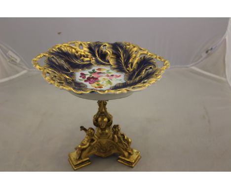 A 19th Century ormolu comport plinth, three putti on the triple feet and supporting the central column, ceramic dish, height 