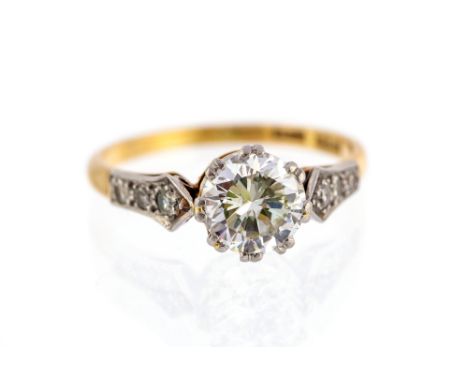 A diamond solitaire 18ct gold ring, with diamond set shoulders, the round brilliant-cut diamond approx 1.35cts, assessed colo