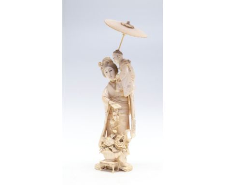 A Japanese ivory okimono of a mother holding an infant upon her shoulder, MEIJI PERIOD 1868-1912, THE INFANT HOLDING A PARASO