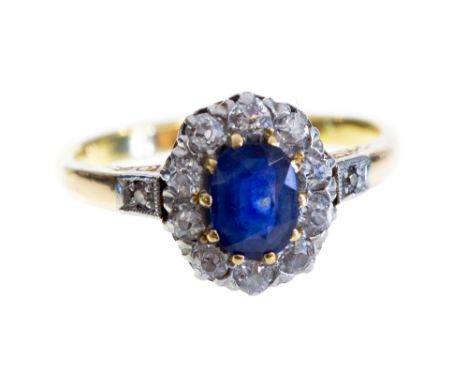 A sapphire and diamond oval cluster ring, yellow gold with diamond set shoulders, the central set oval mixed cut blue sapphir