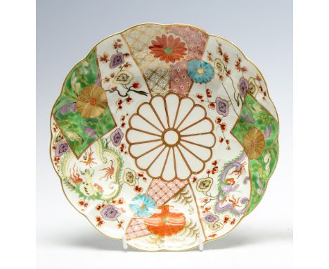 A Worcester deep plate, brocade pattern with a lobed rim, painted in the Japanese taste with panels of dragons, prunus flower