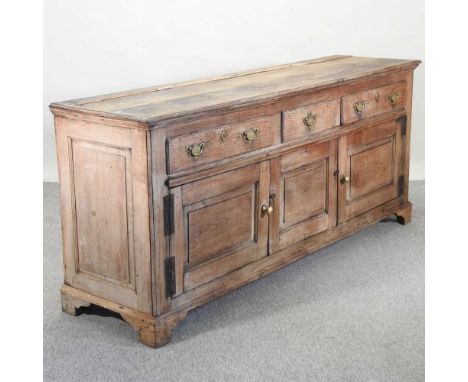 An 18th century oak dresser base, containing three short drawers over three cupboards, on bracket feet,206w x 54d x 89h cm