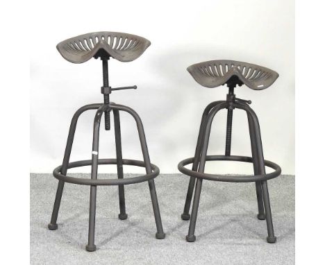 A pair of metal tractor seat stools, with revolving seats