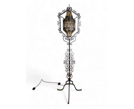 A vintage wrought iron standard lamp
With shaped swinging shade on a scroll work stem, 175cm high.