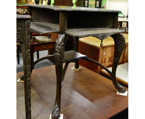 A carved oak occasional table with four fall front frieze compartments on cabriole legs, with a shelf stretcher and ball and 