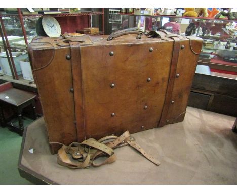 An early 20th Century brown leather suitcase/trunk of large proportions with carrying handle and straps, 81cm wide, 32cm tall