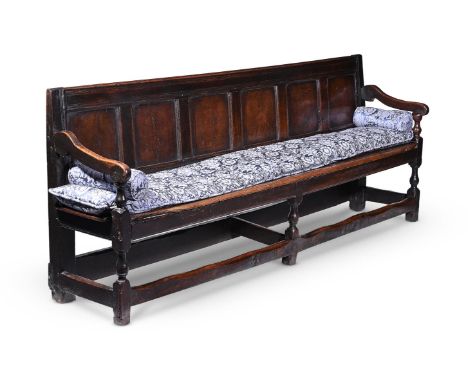 AN OAK SETTLE  EARLY 18TH CENTURY Of long proportion, the six panel back above a long bench seat and baluster supports, 83cm 