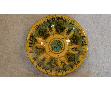 A Persian glazed ceramic dish in green and ochre, dated and marked to base. 6x27