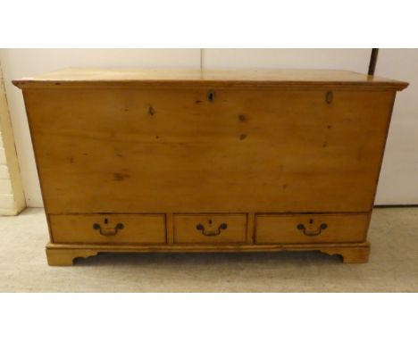 An early 20thC rustic pine trunk with straight sides and a hinged lid with three in-line drawers, raised on bracket feet&nbsp