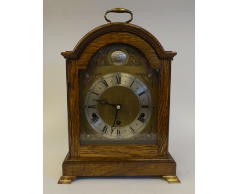 A 20thC Elliot oak cased mantel clock, on a plinth and brass feet; the chiming movement faced by a brushed steel Roman dial&n