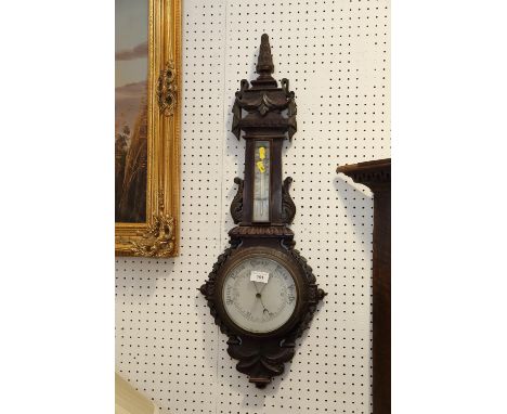 A dark oak barometer and thermometer with carved decoration, 31" high 
