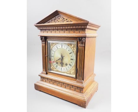 An oak cased mantel clock with carved decoration, silvered and gilt dial, and Roman numerals, on block base, 16 1/2" high 