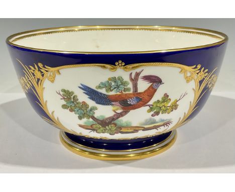 A large Mintons pedestal bowl, printed and painted with reserves of fanciful birds, with raised gilt foliate borders and flor