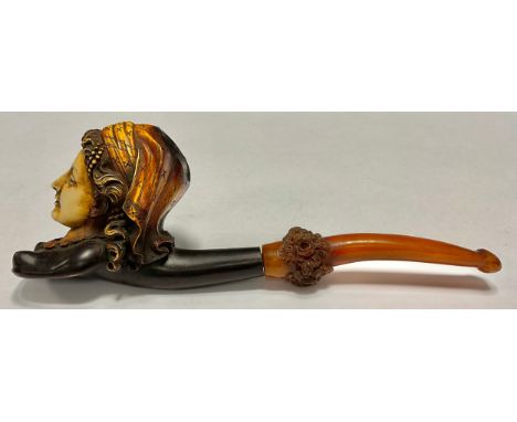 A meeschaum pipe, the bowl as a lady wearing a head scarf, the amber stem carved with flowers, 20cm long, late 19th/early 20t