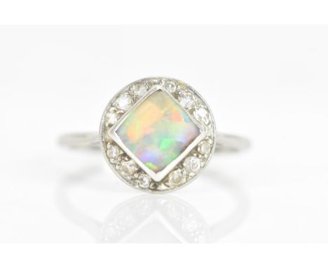 An Art Deco opal platinum and diamond dress ring, the square opal measuring approximately 7mm x 7mm, surrounded by a twelve d