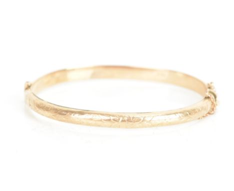 An Edwardian 9ct gold bangle, engraved with a floral design, with a box clasp and safety chain, hallmarked Chester 1908, 63mm