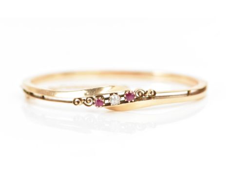 A 14ct gold diamond and ruby bangle, the central brilliant cut diamond approx 3.5mm flanked by two rubies, each in a claw set